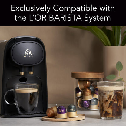 L'OR BARISTA coffee machine with coffee cups and capsules on a table.